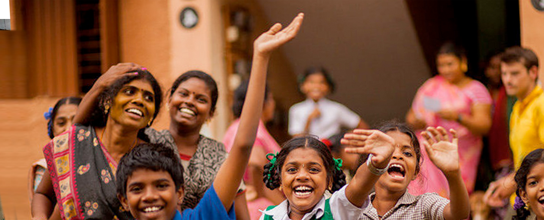 Happy children in India wave at camera.